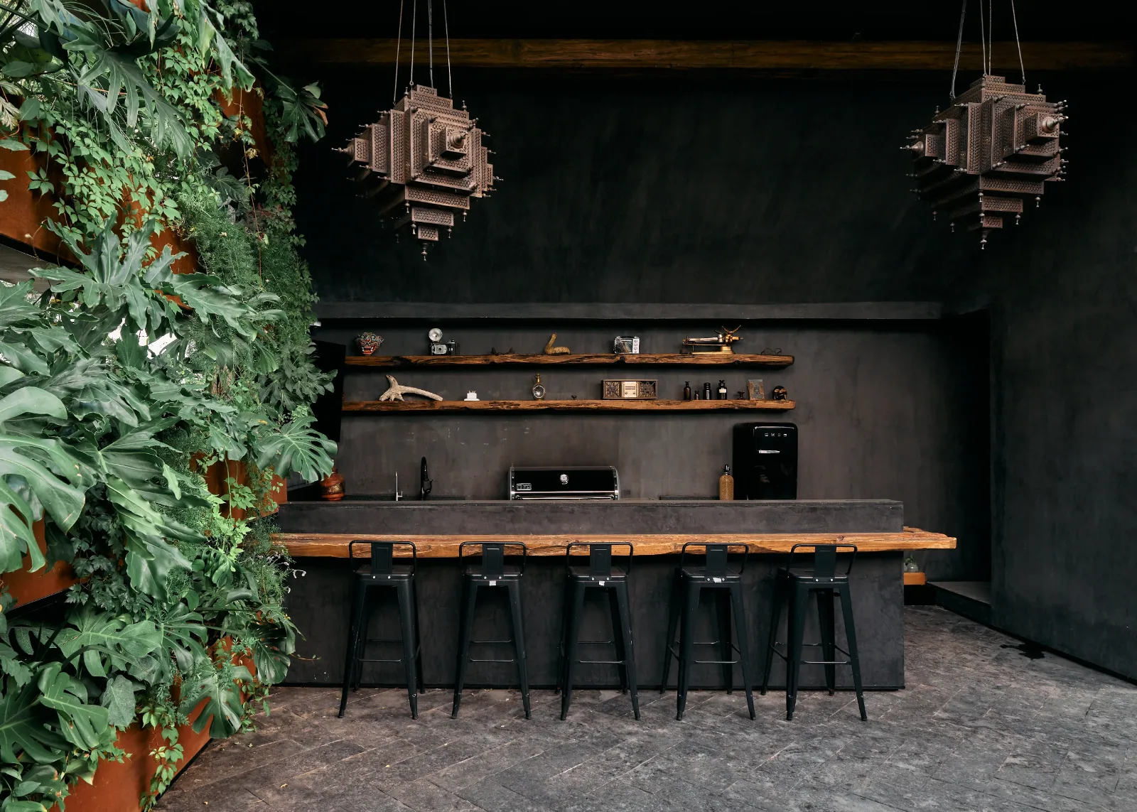 Barra de bar con muro verde y taburetes metálicos fabricados a la medida