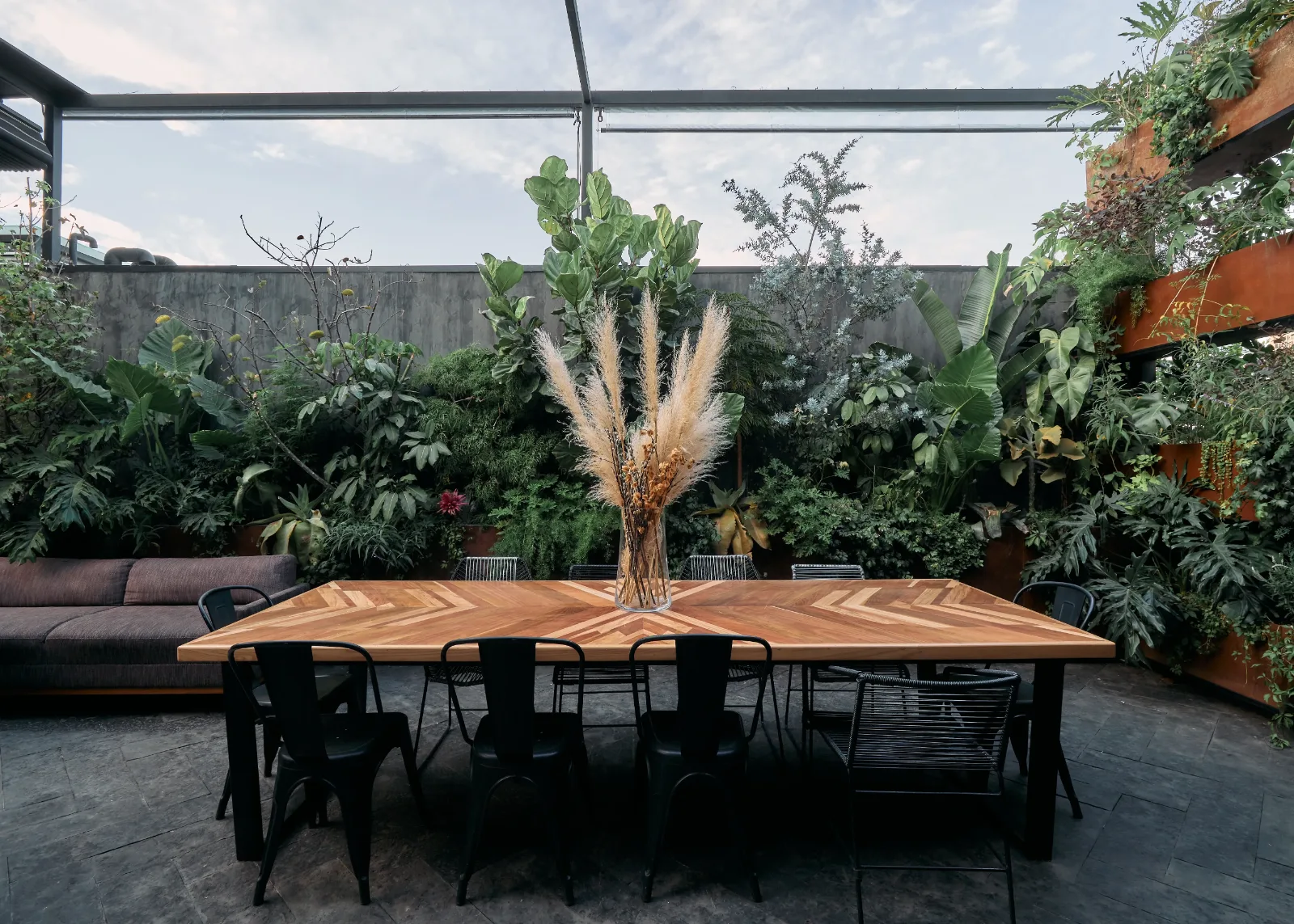 Terraza con mesa larga de madera y bancas metálicas